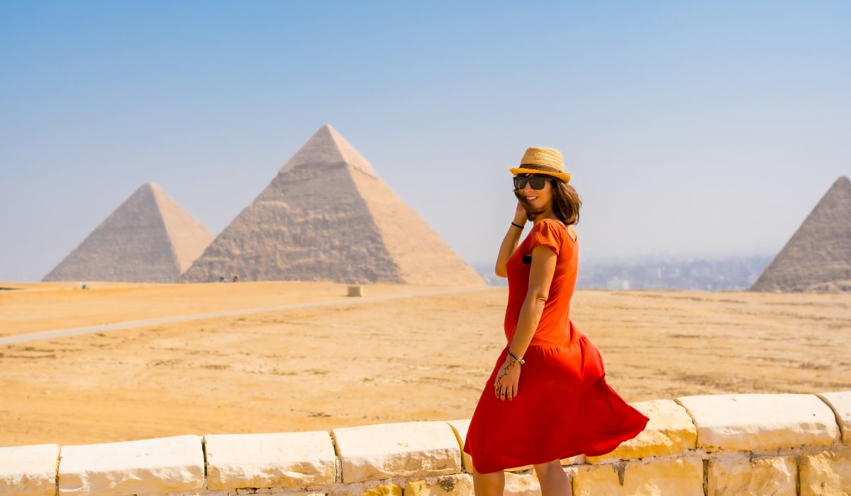 A tourist girl in a red dress at the Pyramids of Giza, the oldest Funerary monument in the world. In the city of Cairo, Egypt